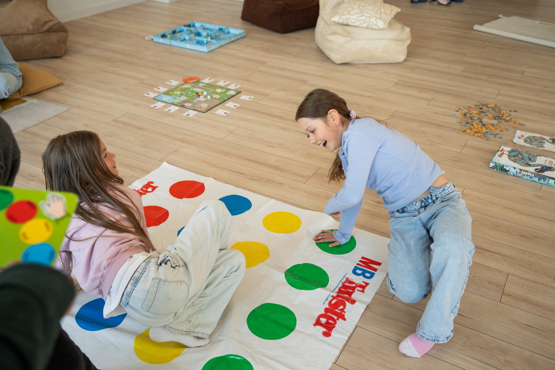 Bērni spēlē Twister mājīgā spēļu telpā